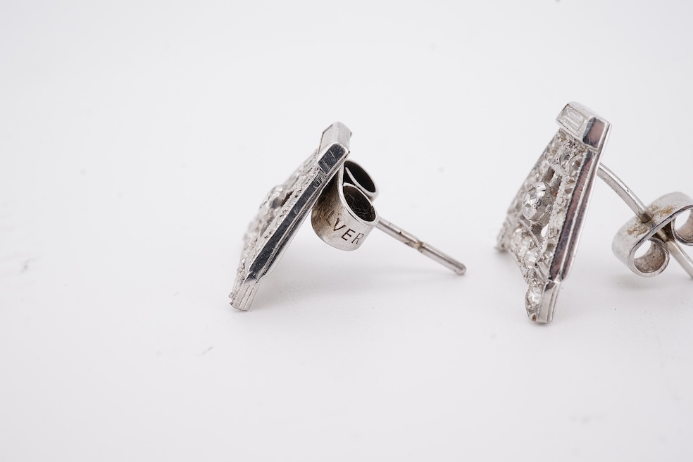 A pair of mid 20th century white metal and millegrain set diamond cluster set 'A' shaped ear studs(adapted from watch lugs?), set with round and baguette cut stones, 12mm, gross weight 3.2 grams.